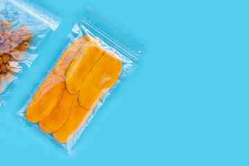 Package with dried mango and dried longan on blue background.