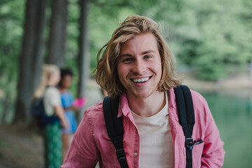 Portrait of young man with friends at background on a hiking or camping trip in the mountains in summer.