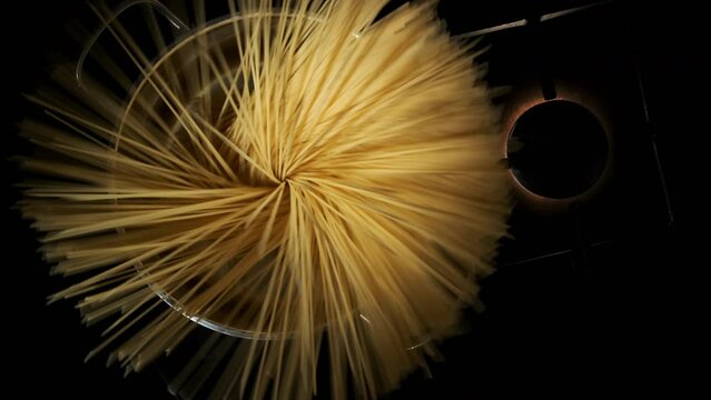 Male chef throwing spaghetti pasta into silver pot on kitchen stove, top view. Italian cuisine food preparation.