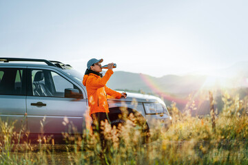 Man drinking coffee by car on mountain
