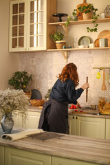 Girl chef cooks in a bright kitchen. Rustic interior. Black kitchen jacket and trousers