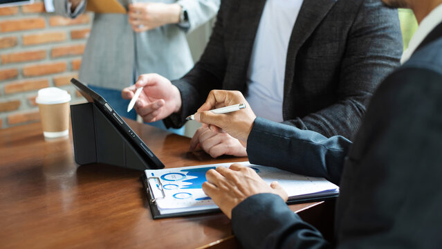 Coworking team meeting.Group of young businessmans working with new startup project while typing on laptop, tablet and writing on notebook