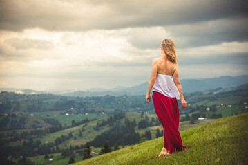 Woman in red at the green fields of Mountains
