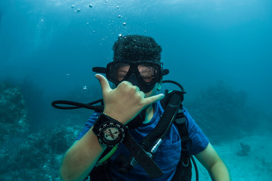 Young Boy Doing Hand Signal, Doing Scuba Diving With A Compass In The Hand