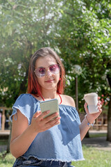 cheerful trendy woman with red hair drinking coffee at park, taking selfie