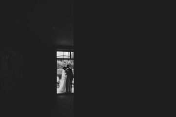 The bride and groom near window. First meeting. Newlyweds kissing indoors. Happy wedding day of marriage. Black and white photo.