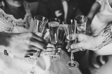 Cheers! People celebrate and raise glasses of wine for toast. Group of men and women cheering with champagne. Black and white photo. Close up.
