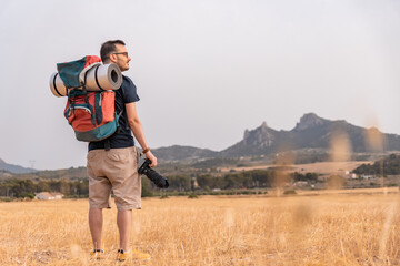 Explorador con cámara de fotografía, mochila con esterilla, con expresión relajada y feliz, en...