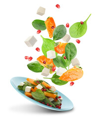 Tasty ingredients for persimmon salad falling into plate on white background