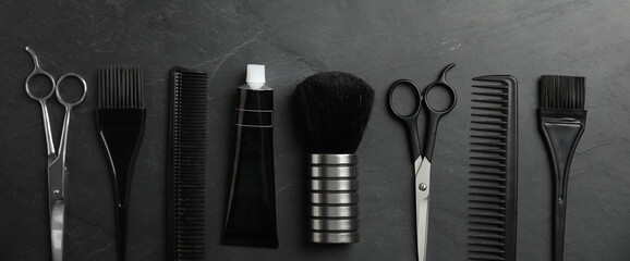 Set of different professional tools for hair dyeing on black stone background, flat lay. Banner...