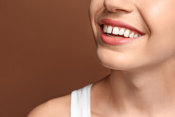 Woman with diastema between upper front teeth on brown background, closeup