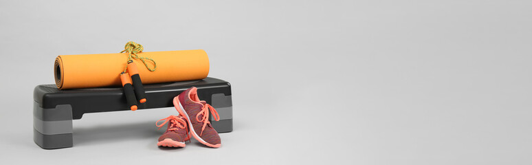 Step platform, yoga mat, skipping rope and sneakers on light background, space for text. Banner...