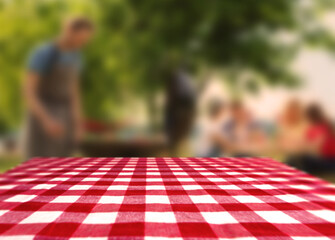 Table with checkered picnic cloth outdoors on sunny day. Space for design