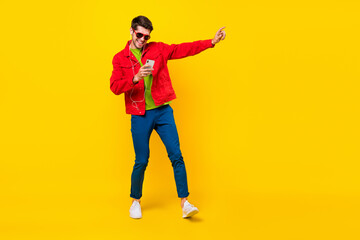 Fototapeta na wymiar Full body photo of cool young guy dance listen music wear glasses jacket pants shoes isolated on yellow background