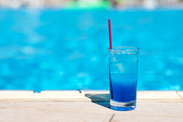 Blue lagoon cocktail with ice near swimming pool. Summer soft drinks.
