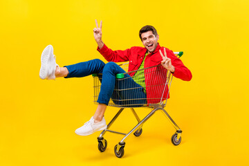Full length body size view of attractive cheerful childish guy riding cart showing v-sign isolated...