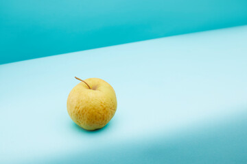 Old, not fresh apple on blue background.