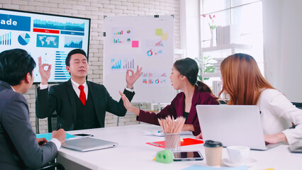 Team leader tries to calm himself while his colleagues are arguing in a meeting.