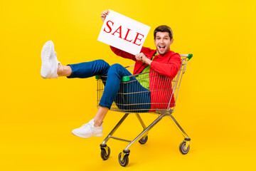 Full length body size view of attractive cheerful guy riding cart holding sale card isolated on...