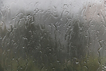Raindrops drip down on the window glass. Soft selective focus.