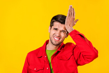 Portrait of attractive stupid guy touching forehead oops trouble isolated over bright yellow color...