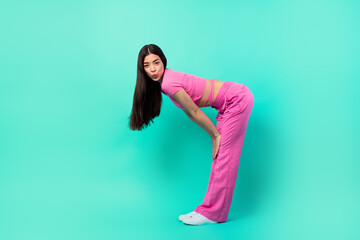 Profile side photo of young girl in casual pink costume and long silky hair flirting on dance floor isolated on teal color background