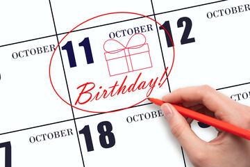 The hand circles the date on the calendar 11 October, draws a gift box and writes the text Birthday. Holiday.