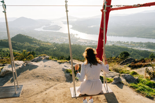 Young woman on a swing looking a beautiful landscape