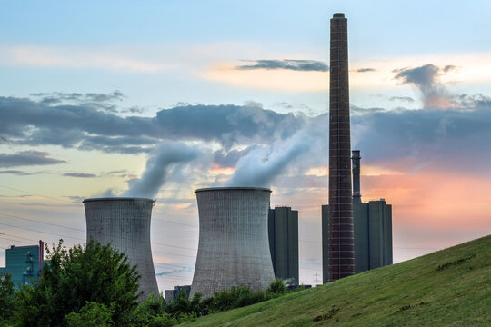 Heavy power plant industry, chimney and towers with pollution at the HKM steelworks in Duisburg, Germany against a cloudy sky at sunset, copy space