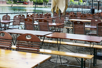 Empty chairs and tables in an attractive outdoor restaurant on the banks of the rhine, staff...