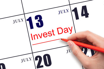 Hand drawing red line and writing the text Invest Day on calendar date July 13. Business and financial concept.