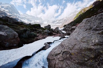 Fototapeta na wymiar Mountain river. Roks and snow with beautiful Alps view.