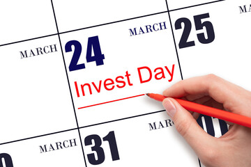 Hand drawing red line and writing the text Invest Day on calendar date March 24. Business and financial concept.