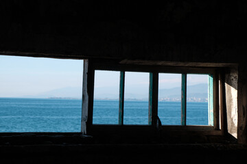 An abandoned concrete building on shores of beautiful blue sea. Environmental impact.