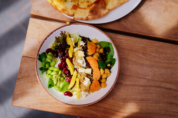 Salad with pumpkin, mango, beans,  lettuce and tofu on a wooden table. Healthy vegetarian food.