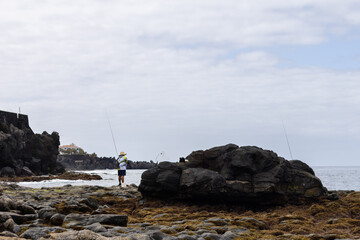 Fototapeta premium Unrecognisable fisherman in the morning. Volcanic rocky beach.