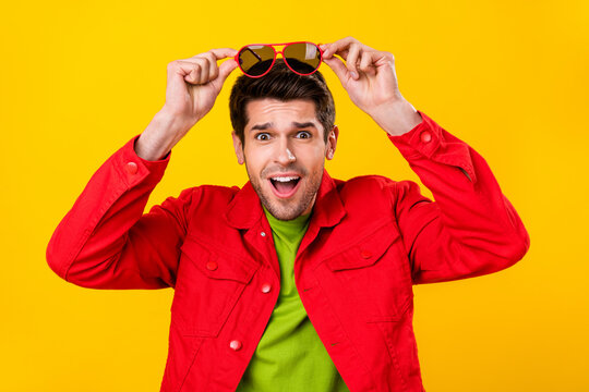 Photo of cool millennial brunet guy hold eyewear wear red shirt isolated on yellow color background