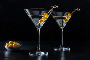 Martini, two glasses with spicy olives, on a dark background. Alcoholic cocktail, side view