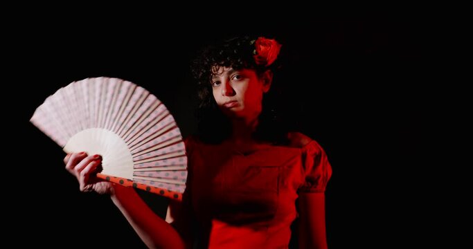A spanish young lady with a fan shot in slow motion in a dark room