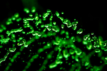 Drops of water splash green water on a black background, concept of freshness drink, watering the rain source of pure water fountain copy space
