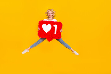 Full length photo of funky millennial blond lady jump hold toy wear shirt jeans footwear isolated on yellow background