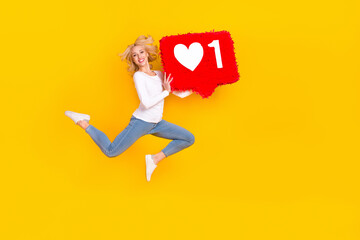 Full size photo of cool young blond lady jump with like wear shirt jeans shoes isolated on yellow background