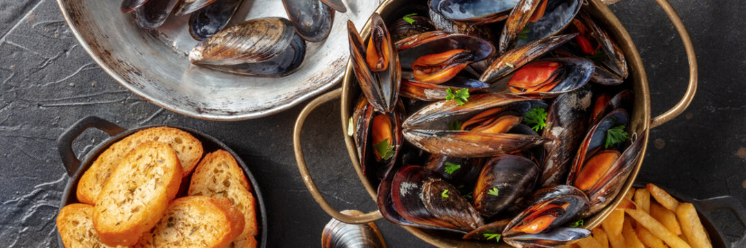 Mussels Panoramic Banner. Seafood Dinner With Shellfish And Toasted Bread, Shot From Above On A Dark Background