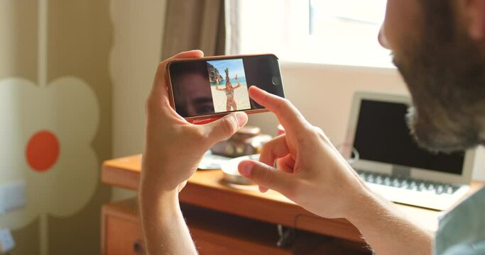 A man looking through photos on his smartphone at home