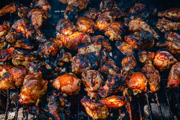 Obraz na płótnie Canvas Spicy chicken legs and wings grilling in a portable barbecue.
