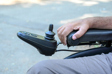 A person with a disability operates a wheelchair. Man using joystick to drive electric wheelchair,...