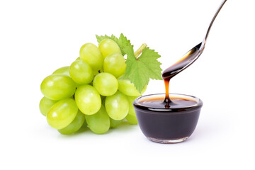 Grape molasses in glass bowl and bunch of green grape with leaf isolated on white background.