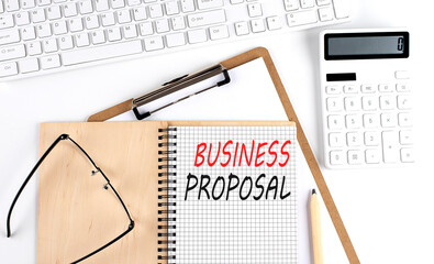 Notebook with the word BUSINESS PROPOSAL with keyboard and calculator on the white background