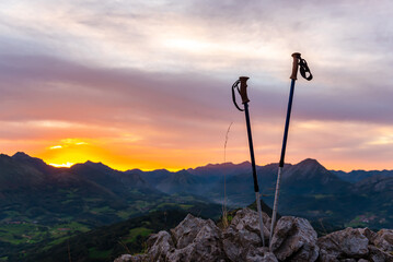 trekking poles without people, placed on a rock on the mountain at sunset. Concept of hiking, trekking and mountain sports activities.