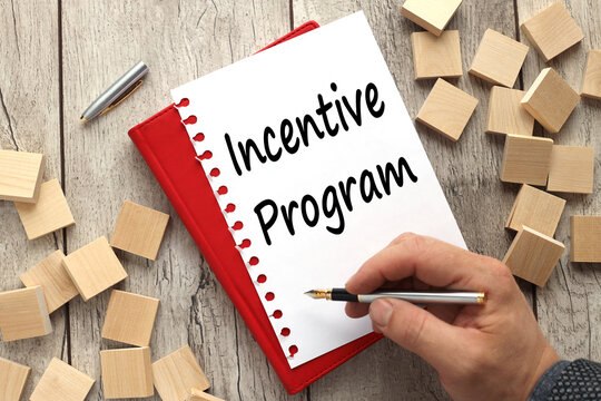 On a wooden surface like a pen and a notebook with an inscription - An incentive program. the text is written by a man's hand